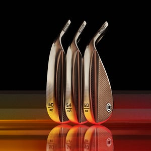 Three shiny, metallic golf wedges with engraved numbers and text are displayed upright in a row against a black background with warm orange reflections on the surface below them.