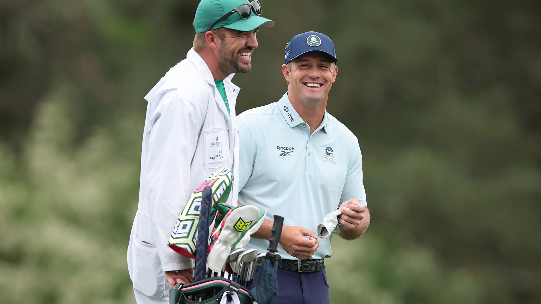 Bryson DeChambeau of the United States laughs with his caddie Greg Bodine on the 15th hole during a practice round prior to the 2026 Masters Tournament at Augusta National Golf Club on April 06, 2026 in Augusta, Georgia