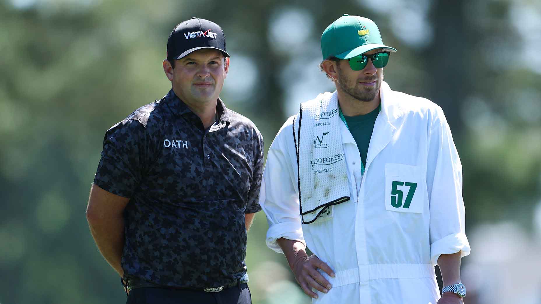 Patrick Reed and his caddie look on during the first round of the 2026 Masters.
