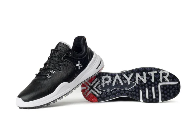 A pair of black and white athletic shoes, with one shoe upright and the other lying on its side, showcasing the sole with the word PAYNTR and a cross design—perfect contenders for the best golf shoes 2026.