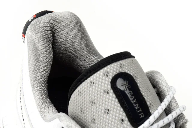Close-up of the heel and tongue of a white and gray sneaker with PAMNIR branding, featuring textured gray padding and white laces—designed with inspiration from the best golf shoes 2026, showcased against a clean white background.