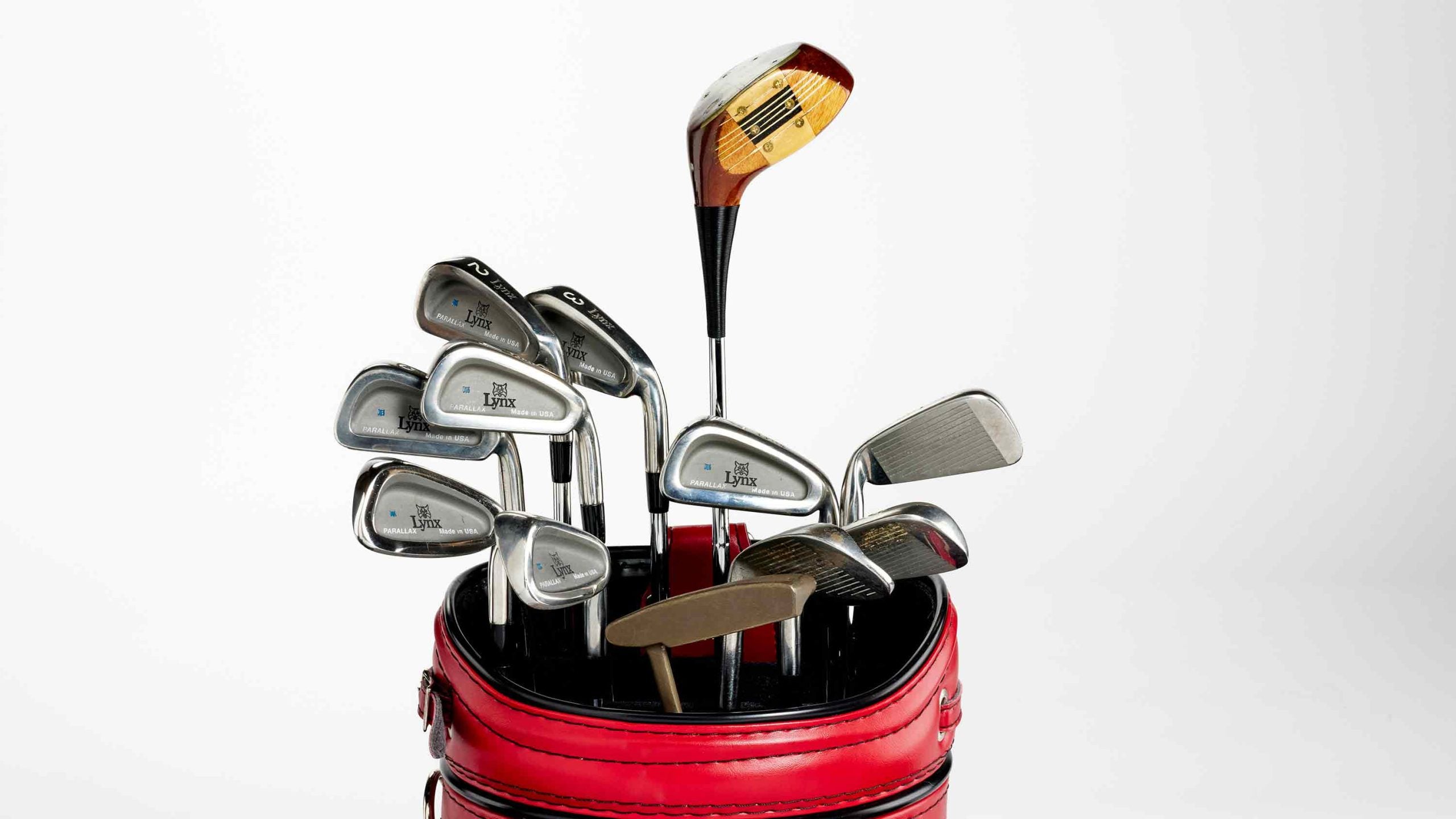 A set of golf clubs with metal and wooden heads sits in a red golf bag against a white background, reminiscent of those Fred Couples might have used during his legendary 1992 Masters win—perhaps with a touch of divine intervention.