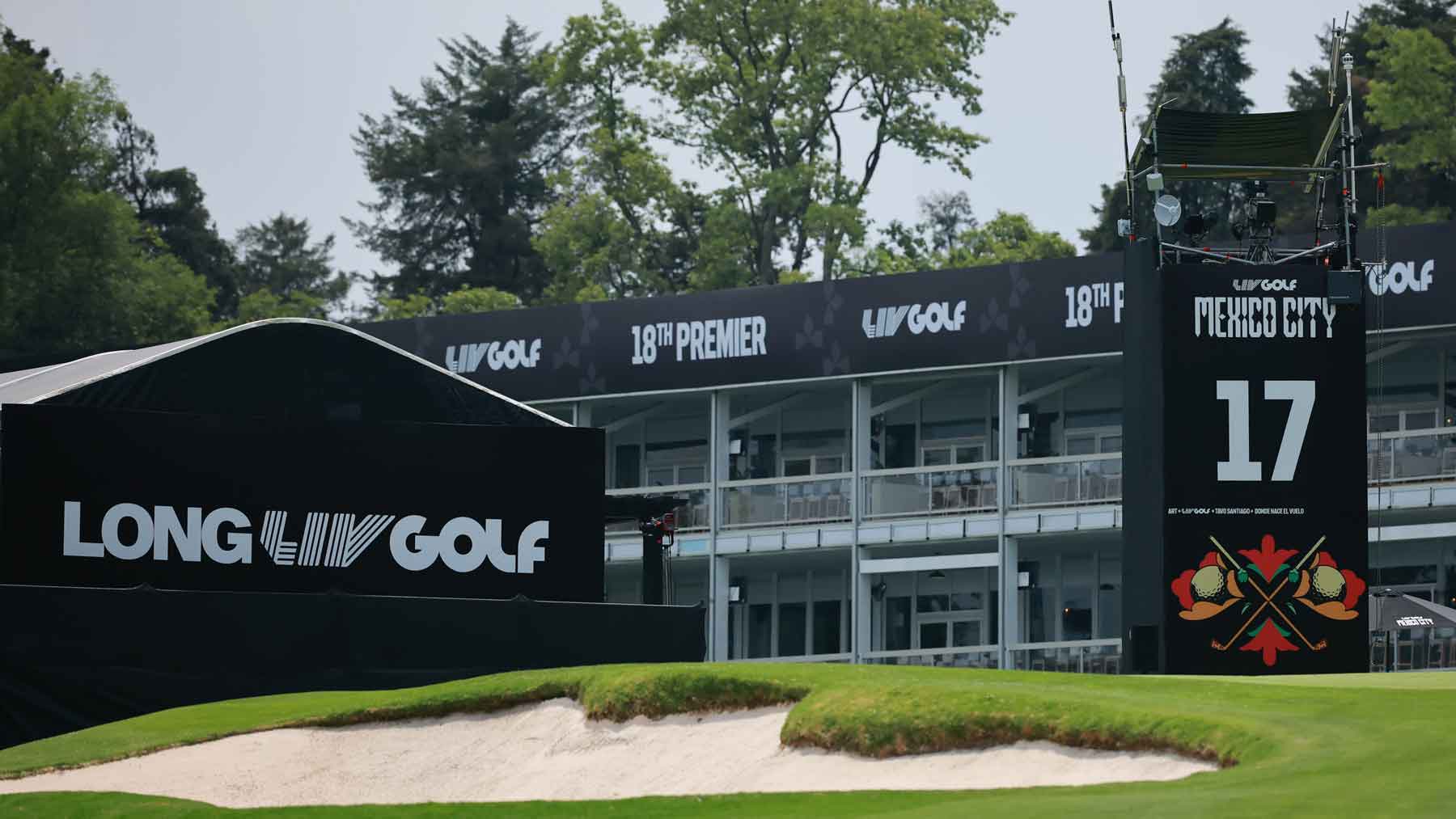 A view of the 17th hole at a LIV Golf event in Mexico City during the season, featuring large black signs with LONG and LIV GOLF logos, a leaderboard, and a sand bunker in the foreground.