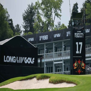 A view of the 17th hole at a LIV Golf event in Mexico City during the season, featuring large black signs with LONG and LIV GOLF logos, a leaderboard, and a sand bunker in the foreground.