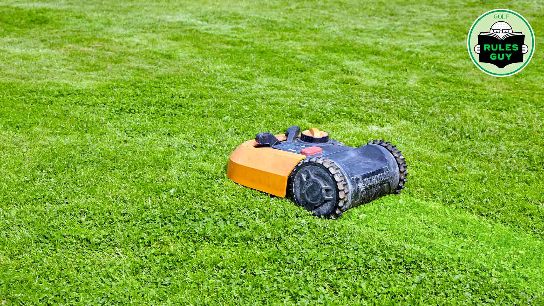 A small robotic lawn mower with orange and black casing moves across a well-manicured green lawn. A circular Golf Rules Guy logo appears in the top right corner.