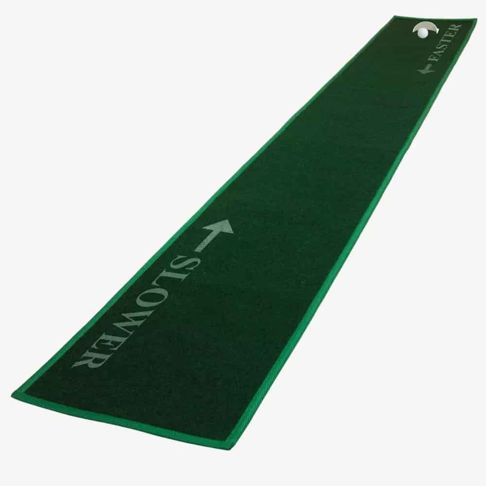 A long, narrow green putting mat with a golf hole at one end. The mat features arrows and the words SLOWER and FASTER for different speed zones—perfect for honing your skills before packing up your gear in the best golf bags 2026.