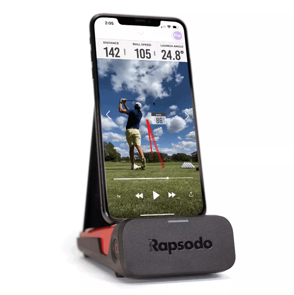 A smartphone on a Rapsodo stand displays a golf swing analysis app, showing a golfer mid-swing on the course with stats like distance, ball speed, and launch angle—all while highlighting the best deals under $50.