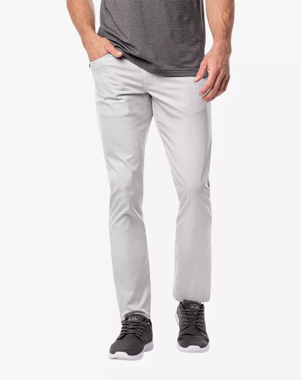 A person wearing light gray slim-fit pants, a dark gray t-shirt, and dark gray sneakers stands against a plain white background—ideal attire for browsing the best golf travel bags. The person's head is not visible in the image.