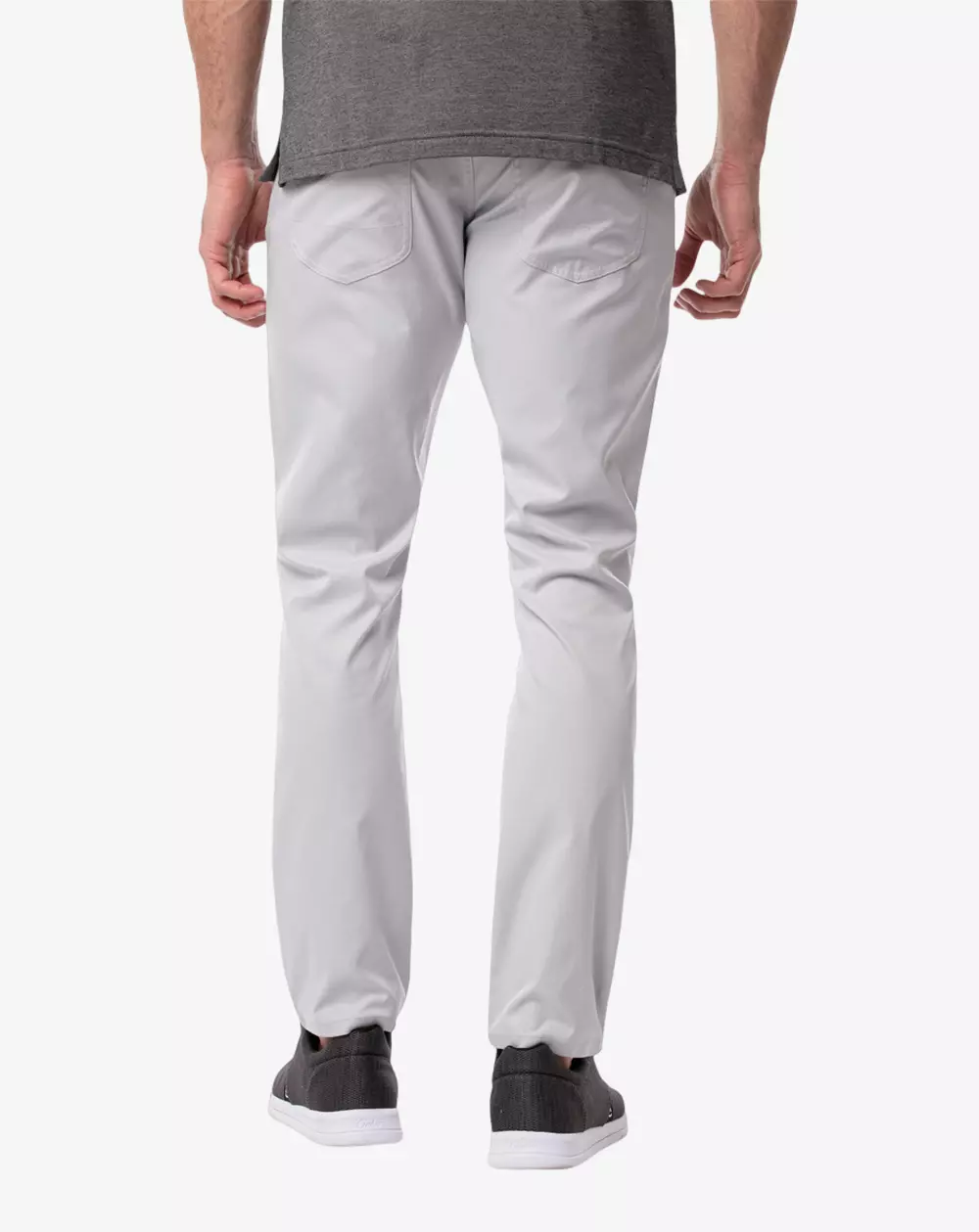 A man is shown from the back wearing light gray pants, a gray t-shirt, and dark sneakers with white soles, standing against a plain white background—perfect attire for organizing essentials before packing into the best golf travel bags.