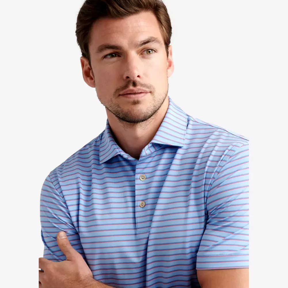 A man with light skin, short brown hair, and light facial hair is wearing a light blue polo shirt with pink and white stripes—perfect for those searching for the best deals under $50. He is looking slightly to his left with a neutral expression.