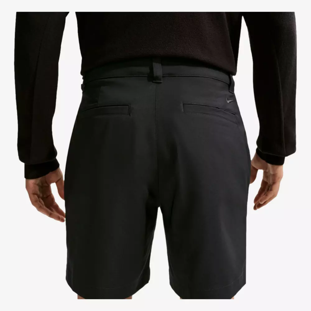 A person wearing a black long-sleeve shirt and black shorts is shown from the back, with hands relaxed by their sides. Popular among those searching for the best golf travel bags, these shorts have belt loops and two back pockets.
