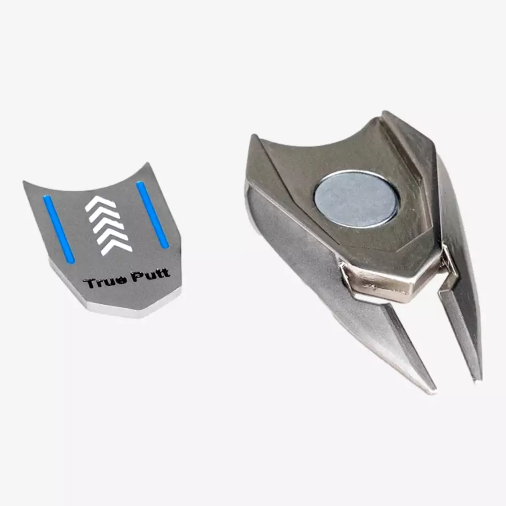A metallic golf divot repair tool with a removable magnetic ball marker labeled True Putt, featuring blue lines and white arrows—an ideal accessory for golfers seeking the best golf bags 2026—shown on a white background.