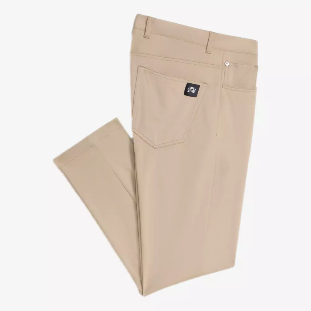 A pair of folded beige pants with a back pocket displaying a black stitched brand tag, laid flat on a white background—perfect for pairing with your best golf travel bags on your next getaway.