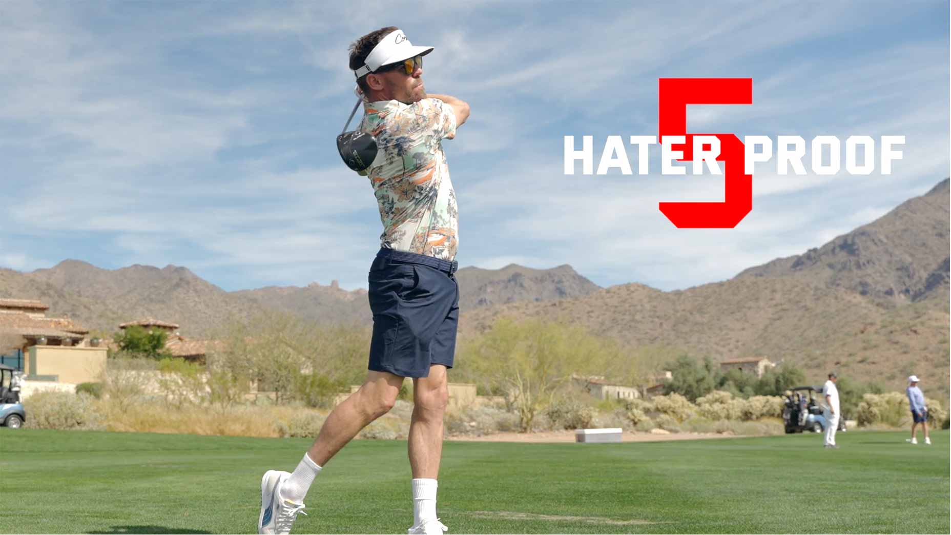 A man in sunglasses, possibly Drew Stoltz, swings a golf club on a green fairway with mountains behind him. Large text reading "5 HATER PROOF" in white and red highlights this hater-proof golf game on the right side of the image.