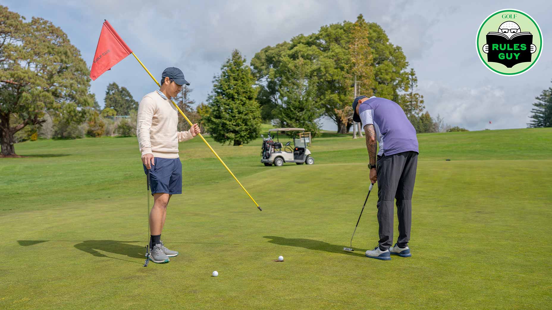 Two men play golf on a green—one putts toward the hole while the other holds a red flag. A golf cart sits in the background, trees surround the course, and a Rules Guy logo appears. Wondering if you can post two scores when playing two balls?.