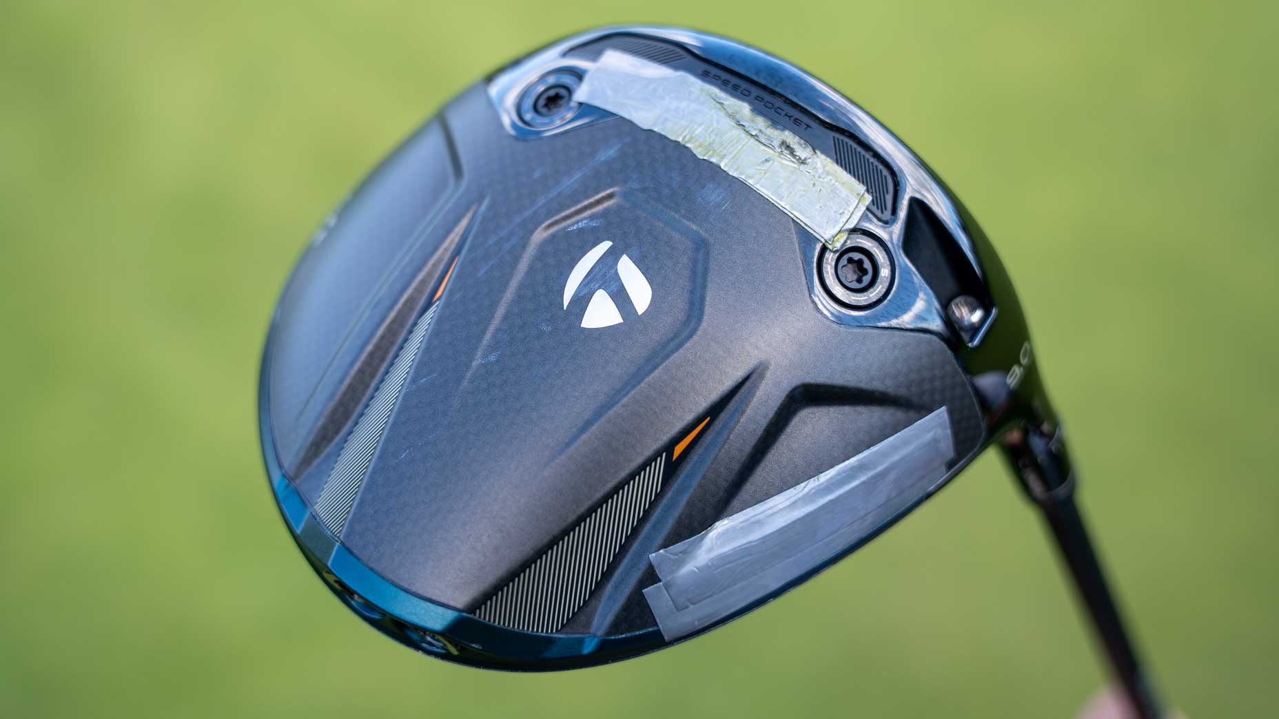 A close-up of a black TaylorMade golf driver head with silver and white detailing, as seen in a recent Tour Report featuring Matt Fitzpatrick, displayed against a blurred green background.