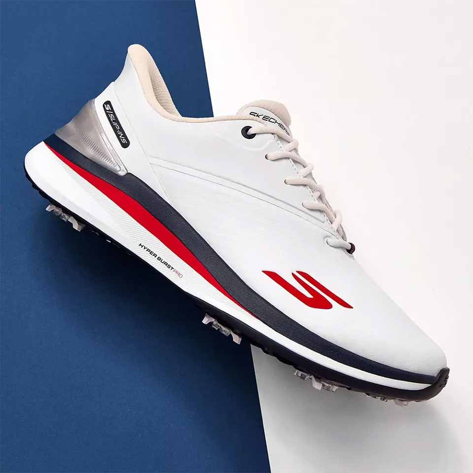 A white athletic shoe with red and navy accents, perfect for patriotic celebration or pairing with red white and blue gear, featuring a bold red logo, navy outsole, and metallic heel detail on a split blue and white background.