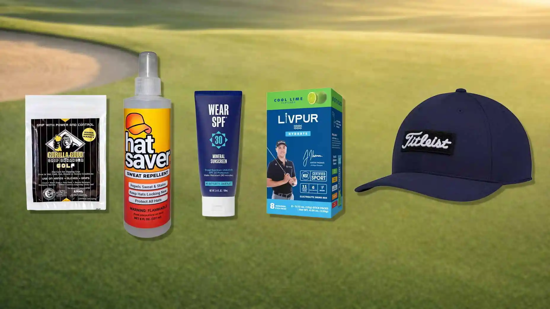 Five golf essentials on a course: gum, hat saver spray, SPF 30 sunscreen, hydration packets, and a navy Titleist cap—all arranged in a row against a blurred golf course background—just like you’d find showcased at the PGA Tour Superstore.