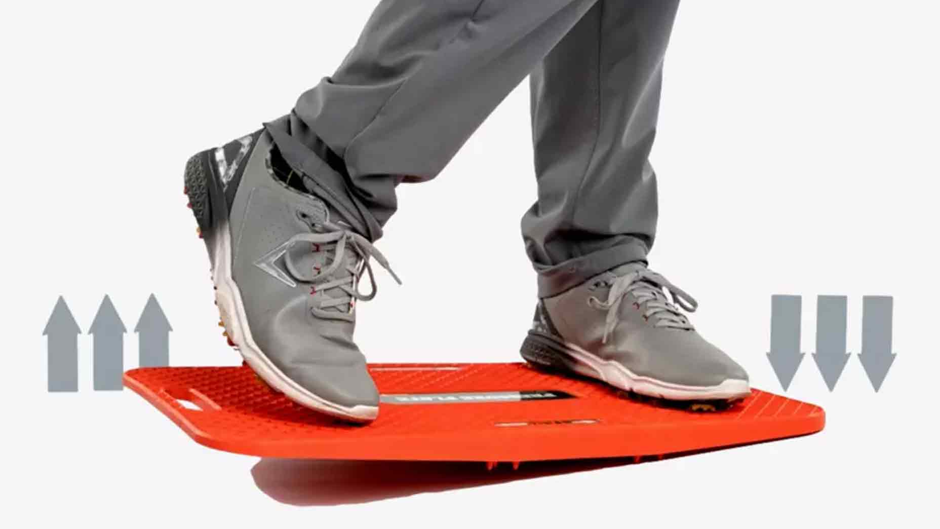 Person balancing on a red wobble board, similar to a pressure plate, while wearing gray sneakers and gray pants; arrows on each side suggest up and down movement.