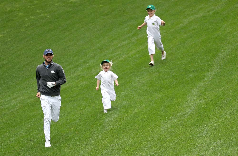 <p>Wesley Bryan runs down a hill during the Masters Par 3 Contest with two young caddies in tow.</p>
